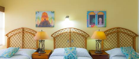 A hotel room with three single beds, each with a wooden headboard and a nightstand. There are two wall-mounted lamps on each nightstand.