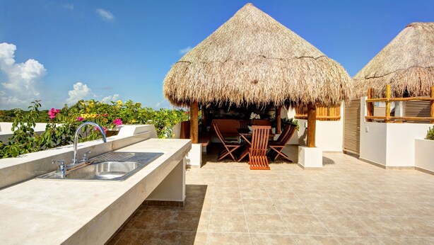 A rooftop terrace with a thatched-roof structure, a sink, and outdoor seating. - Rainbow Penthouse 2 bedrooms sleeps 5 (Tulum)