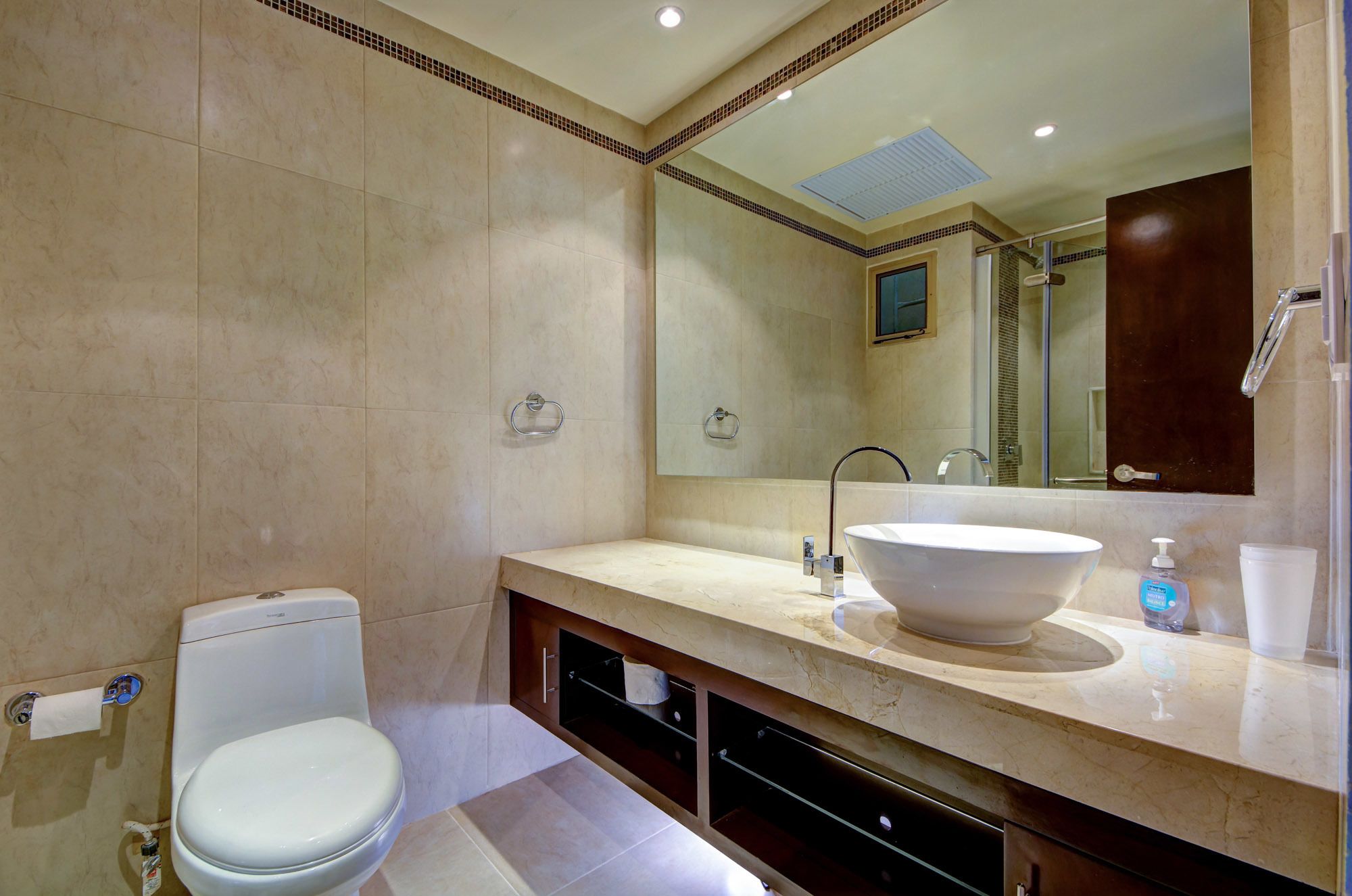 Une salle de bain moderne avec un grand lavabo, des toilettes et un miroir au-dessus du lavabo.