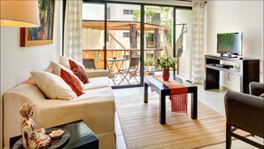 A modern living room with a sofa, a coffee table, and a TV. There is a balcony with a table and chairs. - Anita 2 bedroom apartment sleeps 5 (Tulum)