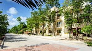 A residential street lined with multi-story buildings, trees, and a clear sky. - Anita 2 bedroom apartment sleeps 5 (Tulum)