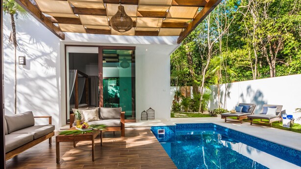 A modern outdoor living area with a pool, wooden furniture, and a view of lush greenery. - Villa Amore 4 bedroom house sleeps 8 (Tulum)