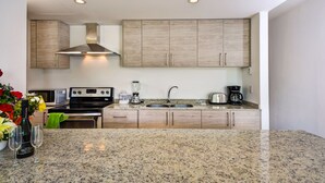 A modern kitchen with granite countertops, stainless steel appliances, and wooden cabinets. - Atthakan 3 bedroom apartment sleeps 10 (Tulum)