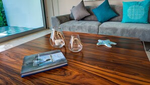 A modern living room with a wooden coffee table, a book, two glass vases, and a decorative starfish. - Atthakan 3 bedroom apartment sleeps 10 (Tulum)