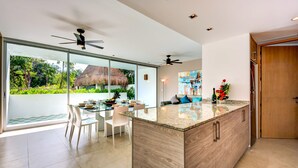 A modern kitchen with a large island, glass doors leading to a garden, and ceiling fans. - Atthakan 3 bedroom apartment sleeps 10 (Tulum)
