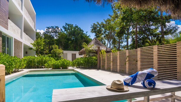 A pool area with a lounge chair, a hat, and a thatched-roof structure. - Atthakan 3 bedroom apartment sleeps 10 (Tulum)