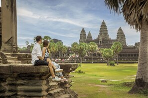 A couple sitting on stone steps overlooking a temple complex with multiple towers. - Courtyard by Marriott Siem Reap Resort (Siem Reap)