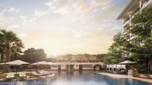 Un espace piscine aménagé dans un complexe hôtelier, avec des chaises longues, des parasols et un bâtiment doté de balcons.