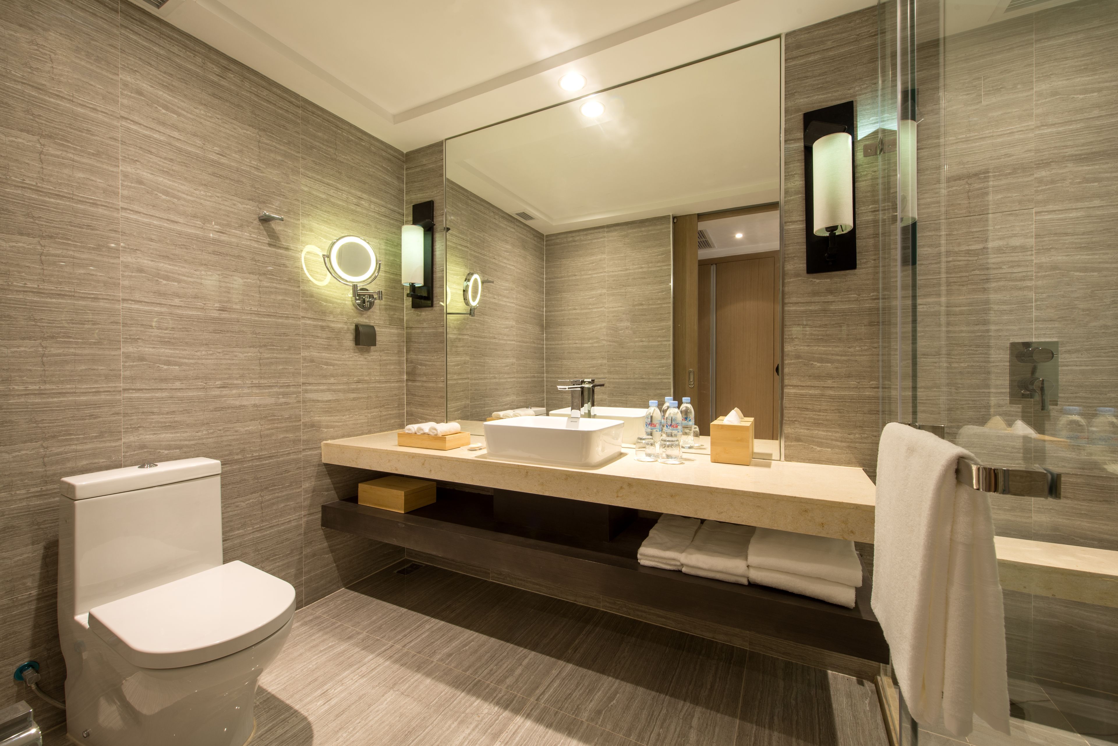 Een moderne badkamer met toilet, wastafel en grote spiegel.