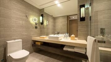 A modern bathroom with a toilet, sink, and large mirror.