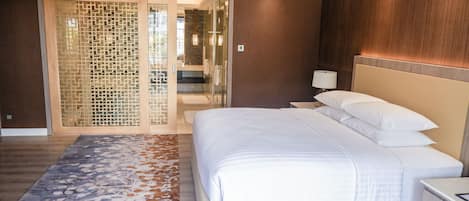 A modern hotel room with a large bed, a nightstand, a lamp, and a decorative wall panel.