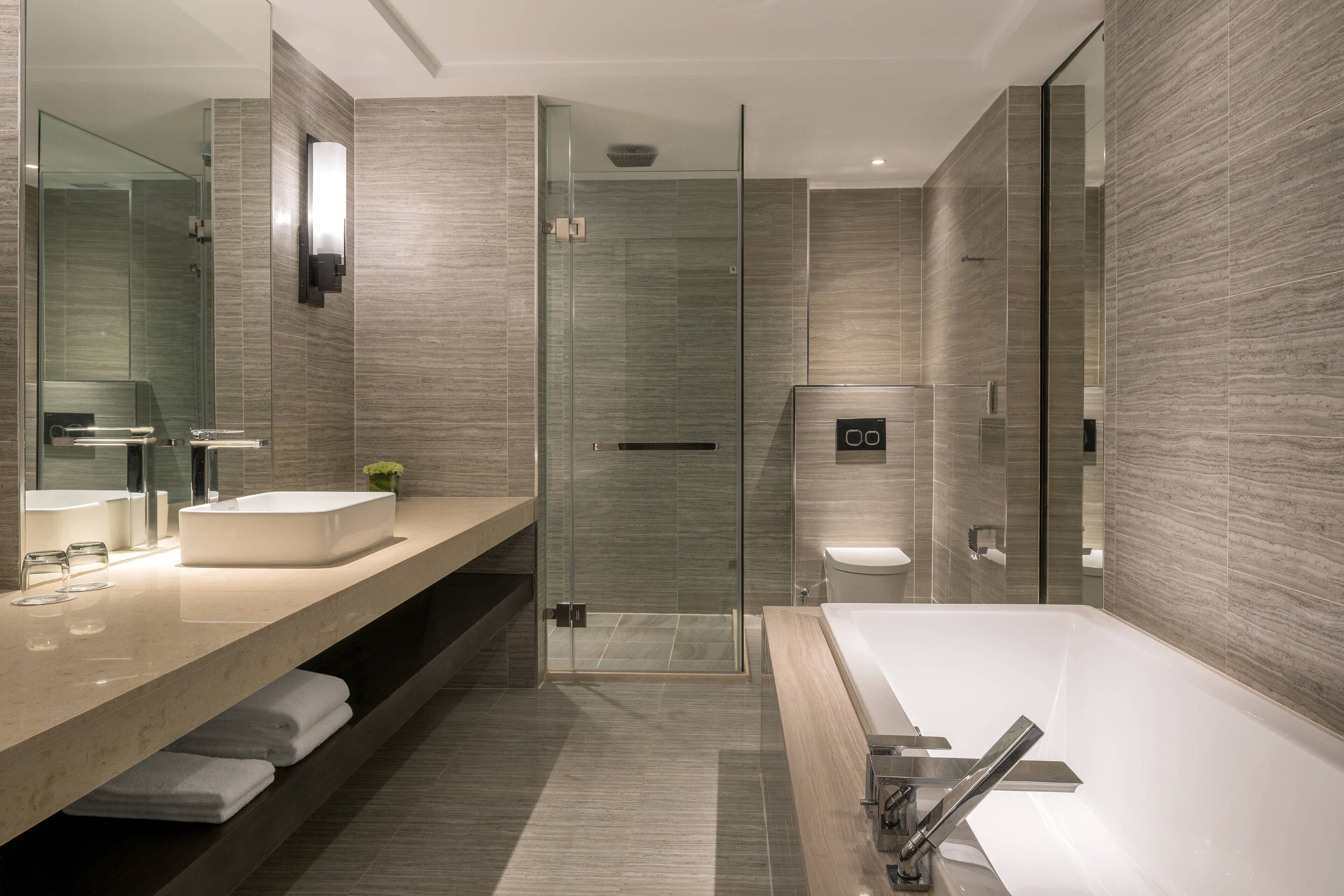 A modern bathroom with a glass-enclosed shower, a large bathtub, and a vanity with a sink and mirror.
