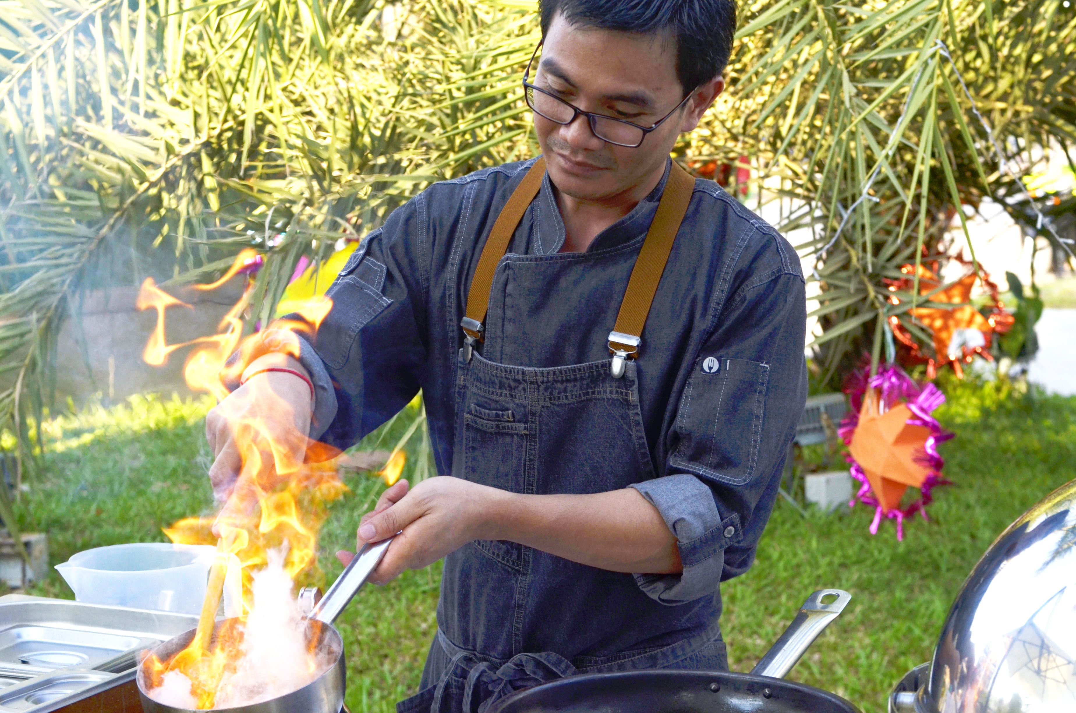 A person cooking outdoors with a pot on a portable stove.