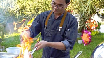 Une personne qui cuisine à l’extérieur, avec une casserole sur un réchaud portatif.