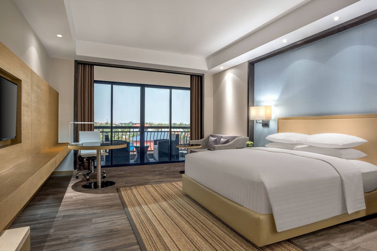 Une chambre d’hôtel moderne dotée d’un grand lit, d’un bureau et d’un balcon avec vue.