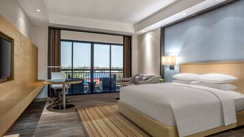 Una habitación de hotel moderna con una cama grande, un escritorio y un balcón con vistas.