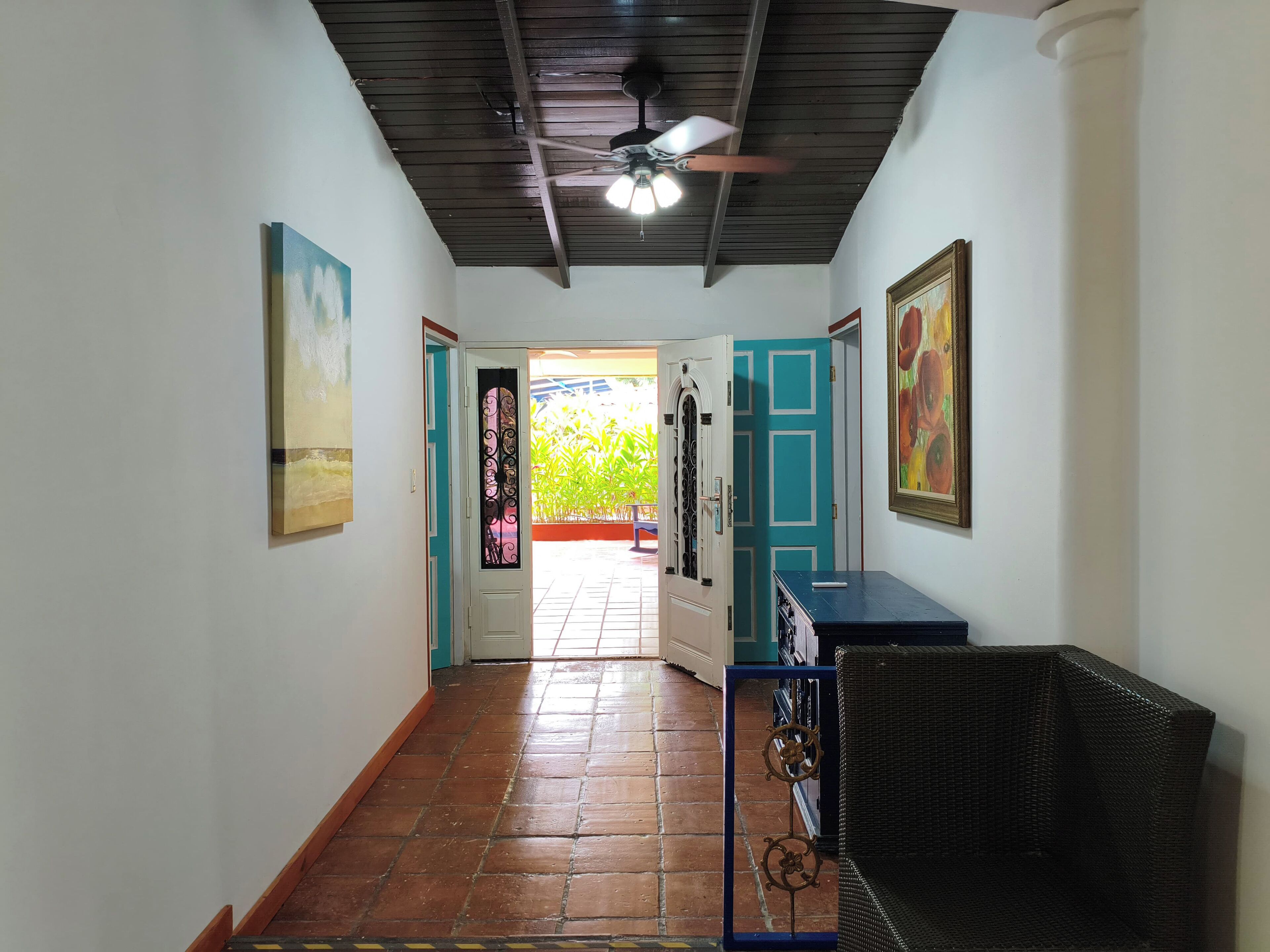 A hallway with a ceiling fan, tiled floor, and doors leading to a balcony.