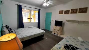 A bedroom with a bed, a nightstand, a television, and a window with curtains.