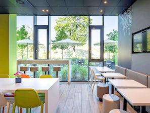 Un restaurant moderne doté de grandes fenêtres, d’une terrasse et d’un intérieur au style minimaliste.