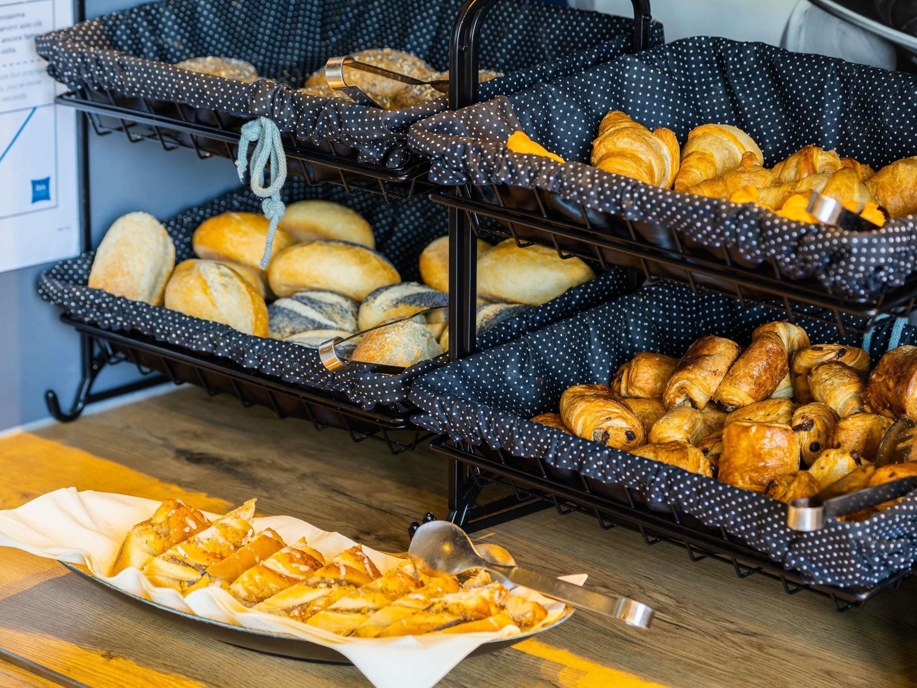 Un bufé con diversas opciones de panadería, incluyendo pan y pasteles, dispuesto sobre una rejilla de metal con manteles de lunares.