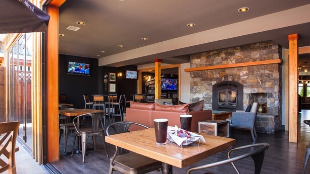 A cozy restaurant with a stone fireplace, wooden tables, and comfortable seating. - The Lodge at Arrow Lakes (Nakusp)