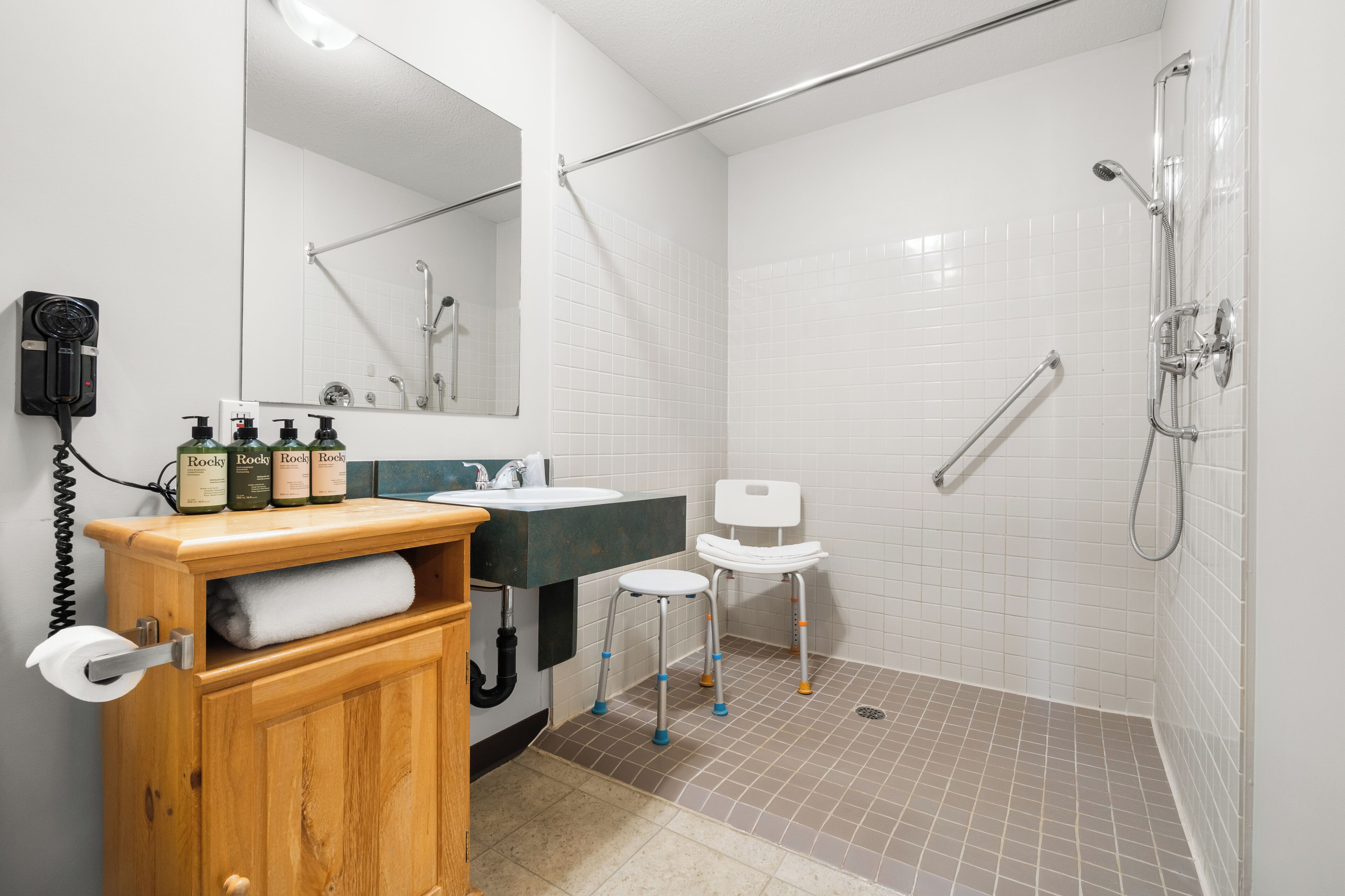 Une salle de bain avec un meuble en bois, un lavabo, un miroir, une douche et des toilettes.