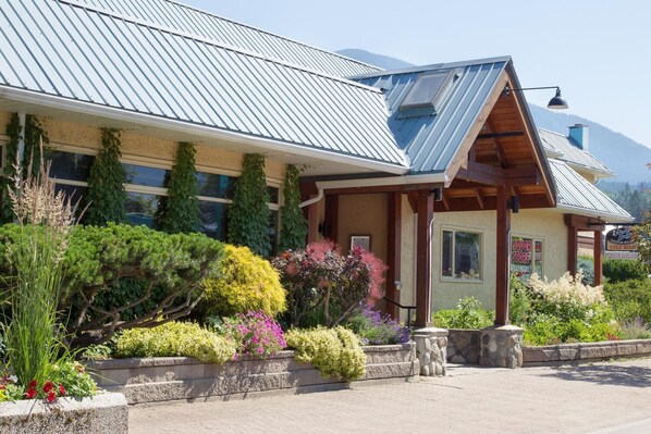 A building with a metal roof, a liquor store sign, and a variety of colorful plants in the front garden.