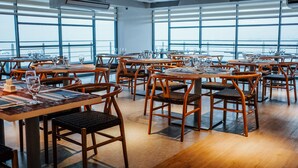 A restaurant with wooden tables and chairs, large windows, and a view of the sky. - TRYP by Wyndham Mall of Asia Manila (Pasay)