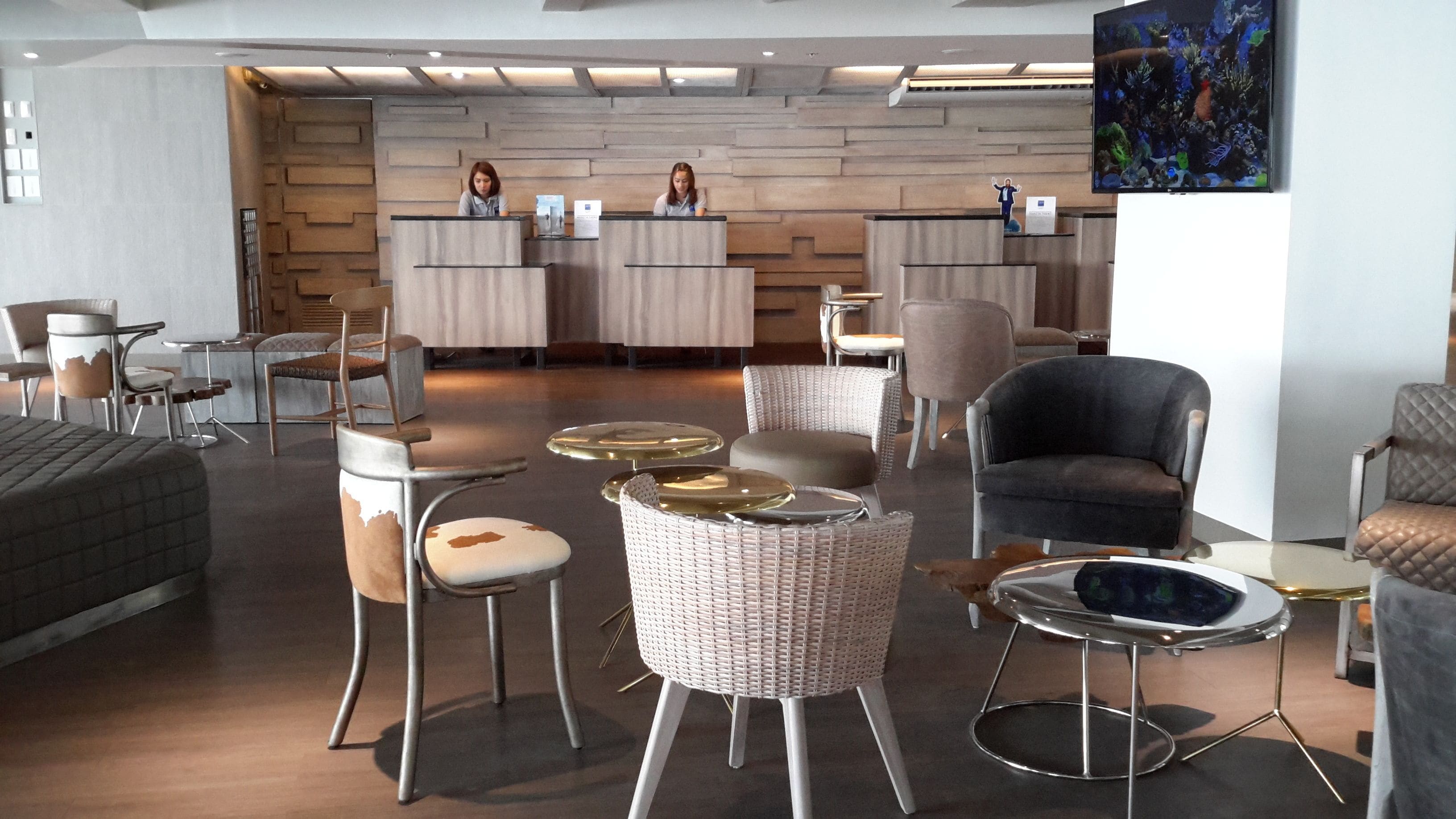 A modern interior with a reception desk, seating area, and a large painting.