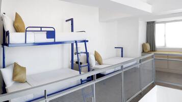 Moderni hotellihuone, jossa on kerrossängyt, parvekkeelta avautuva näköala ja vaatekaappi.