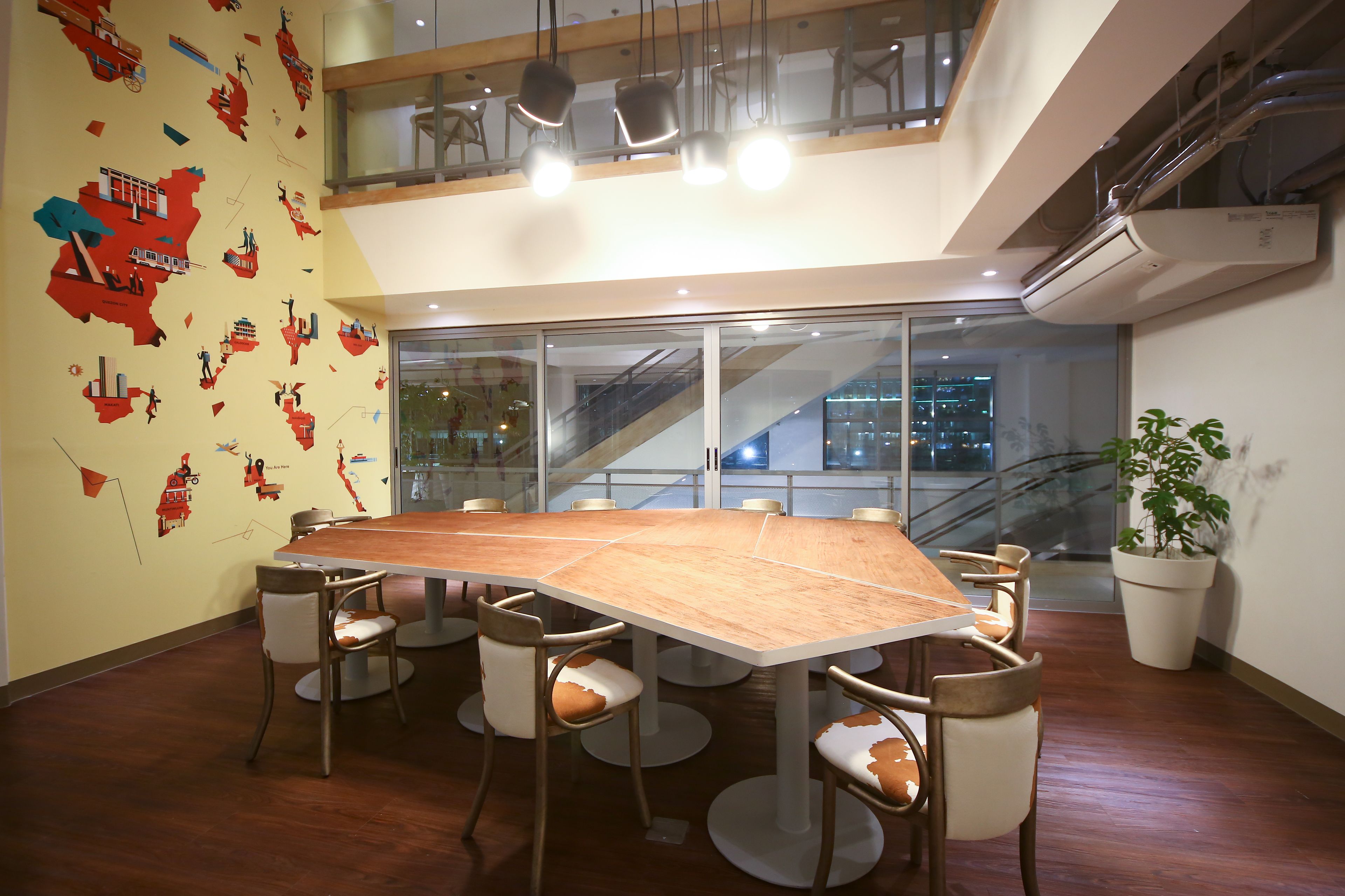 A conference room with a large wooden table, six chairs, and a glass wall with a city view.