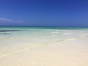 A beach with clear turquoise water and white sand.
