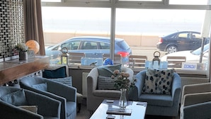 Sala de estar com vista para a praia, mobiliada com sofás e uma mesa de centro.