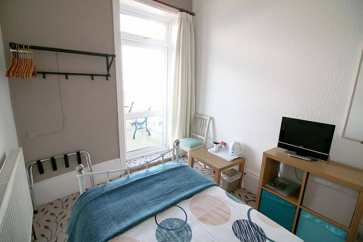 A bedroom with a bed, a TV, a desk, and a chair.