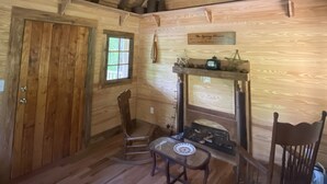 Un intérieur rustique avec des éléments en bois, un plafond en pente, un ventilateur de plafond, une cheminée et des meubles en bois.