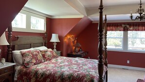 Quarto com cama de dossel, lustre e janela com cortinas.
