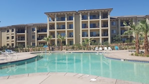 A hotel with a swimming pool, multiple balconies, and palm trees. - Estancia Resort! New beauty in St George with heated pool and pickleball (Saint George)