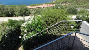 Una escalera conduce a una terraza con vistas al mar y edificios costeros.