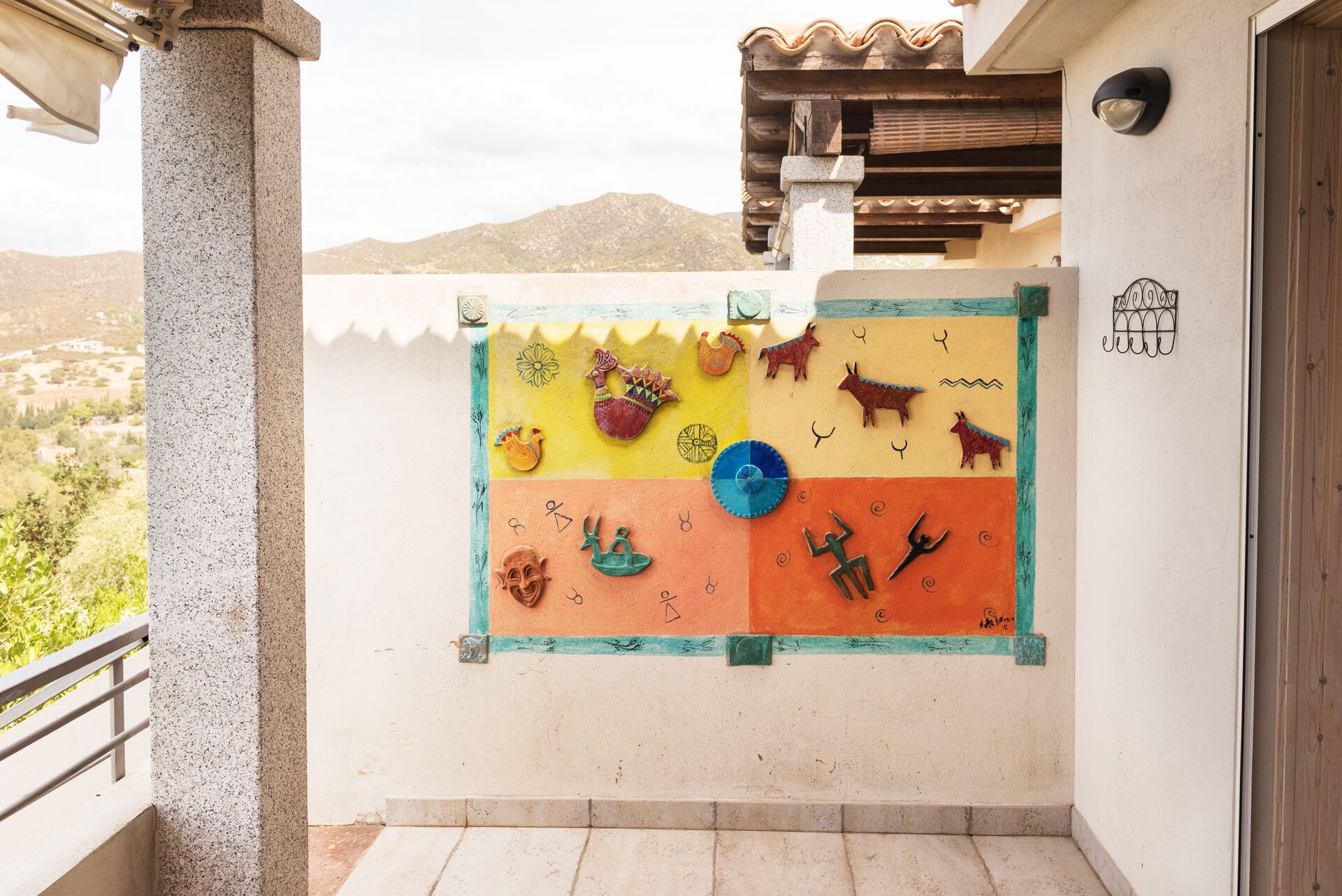 A balcony with a colorful mural featuring various cultural symbols and animals.