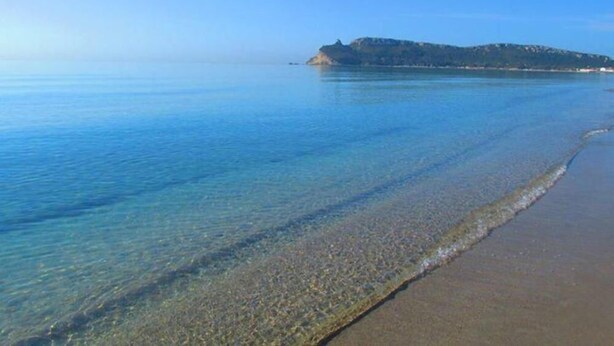 Una vista despejada de una playa con una pequeña isla en la distancia.
