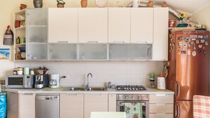Cocina compacta equipada con lavavajillas, microondas, cafetera y estufa a gas.