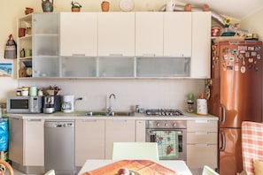 A compact kitchen with a dishwasher, microwave, coffee maker, and gas stove.
