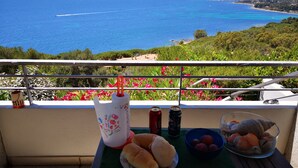 Un balcón con una mesa lista para una comida, con vistas a la costa.