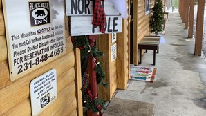 Esterno di un motel in legno con insegne che riportano 'The Rainbow Room' e 'North Pole'.