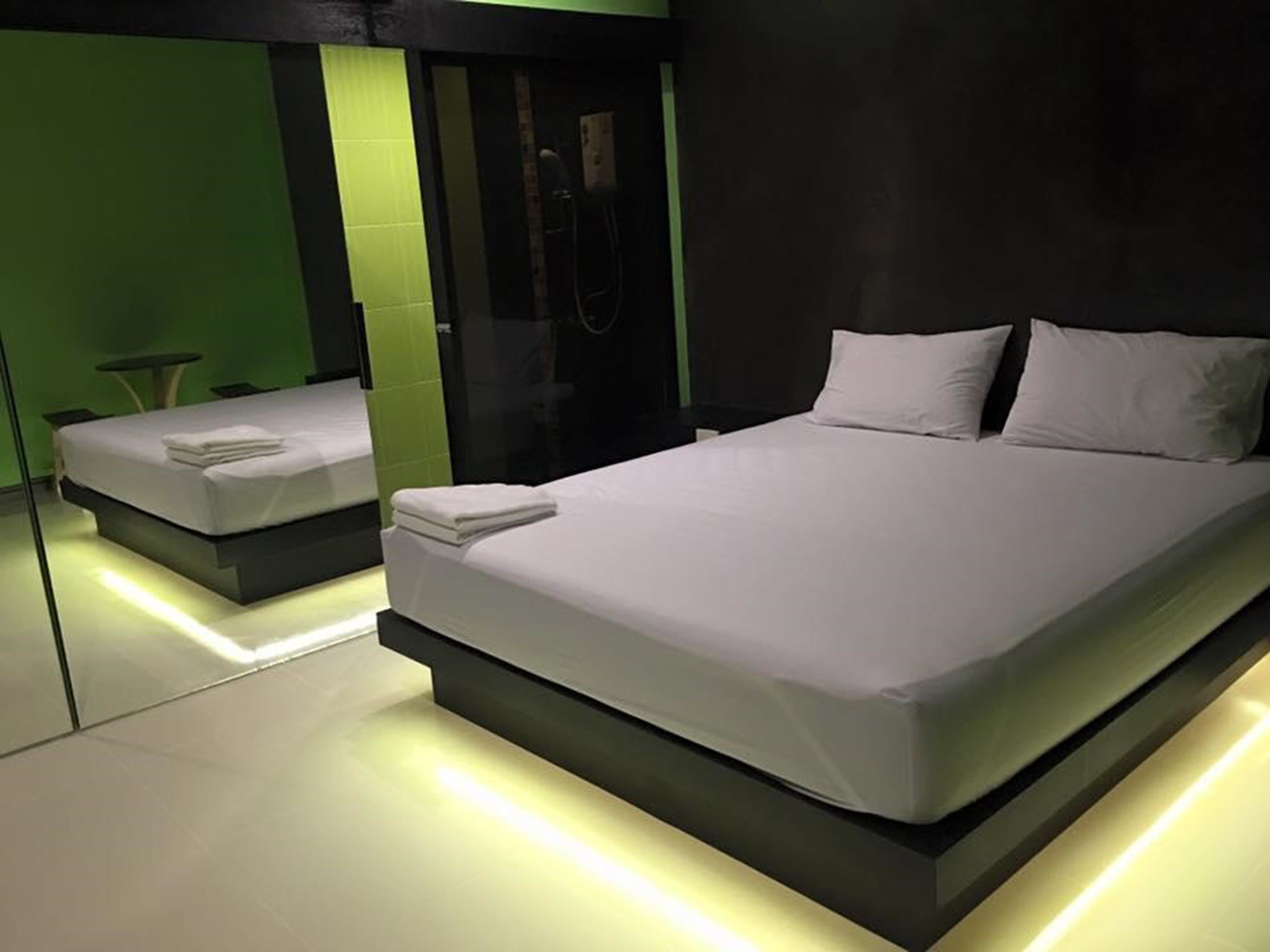 A modern hotel room with a large bed, a smaller bed, and a seating area.