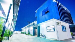 A modern building with a blue facade, a bicycle parked in front, and a clear sky. - i DUS Resort (Phitsanulok)
