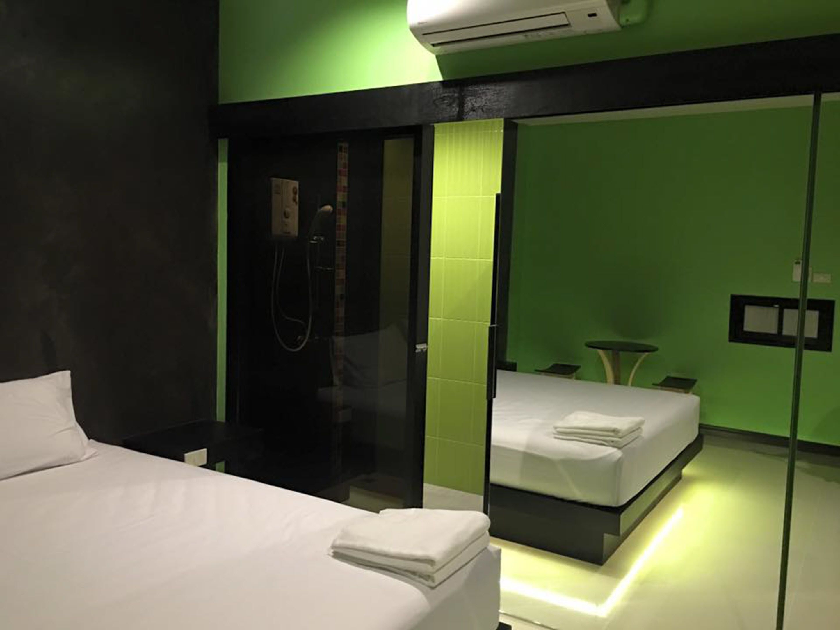 A modern hotel room with a large bed, a separate shower area, and a glass partition.