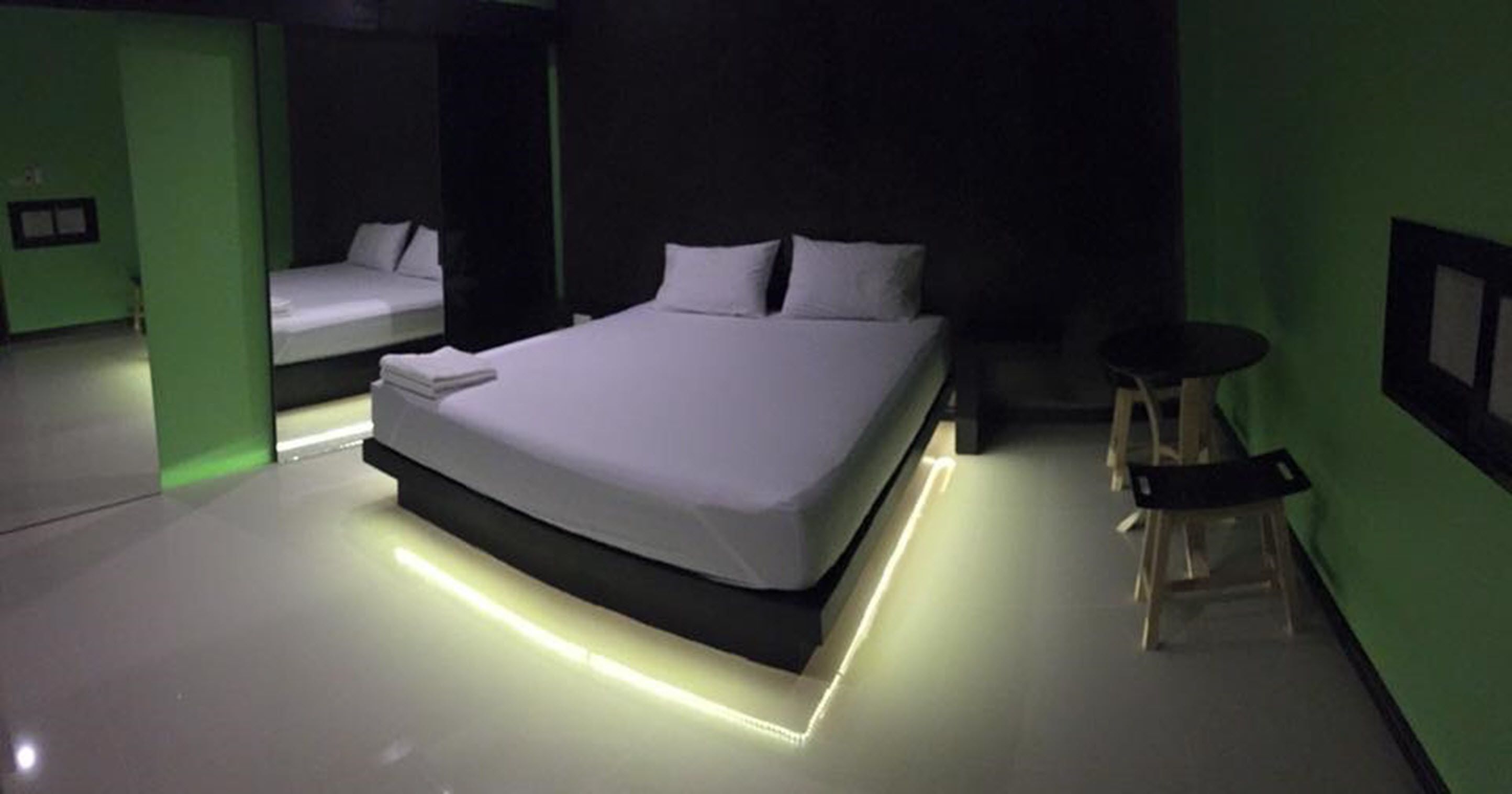 A modern bedroom with a large bed, a small table, and green walls.