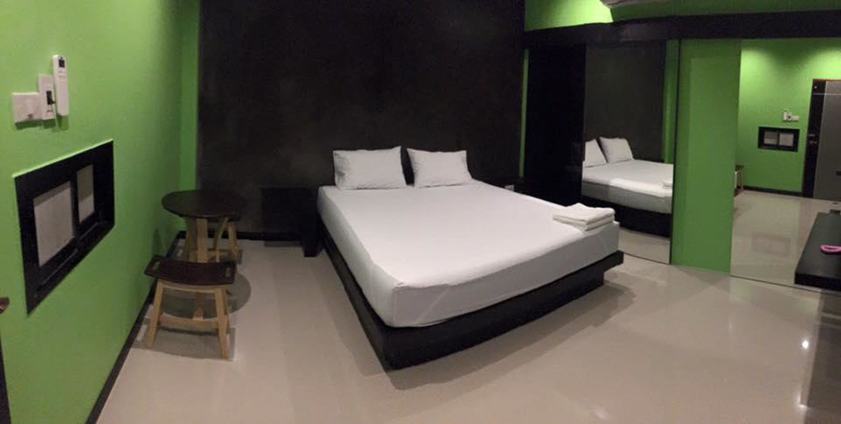 A modern hotel room with a large bed, a small table, and a mirror.