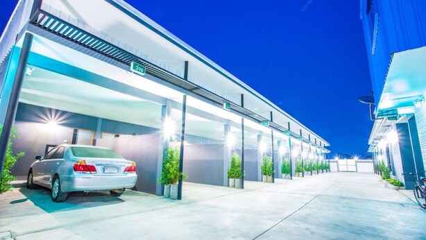 A modern building with a covered parking area, a car, and potted plants. - i DUS Resort (Phitsanulok)